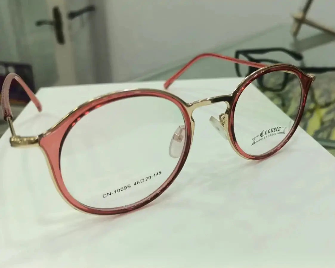 Round pinkish-red with a gold-tone Coonees Label Eyewear